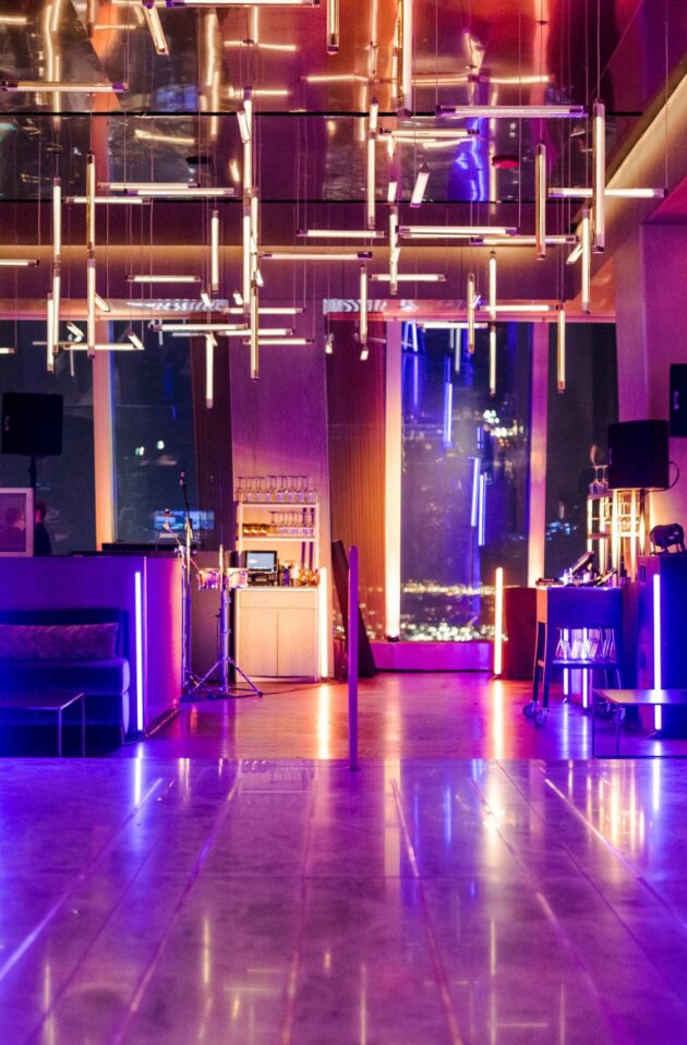 neon lit dancefloor in a lounge in a tall building.