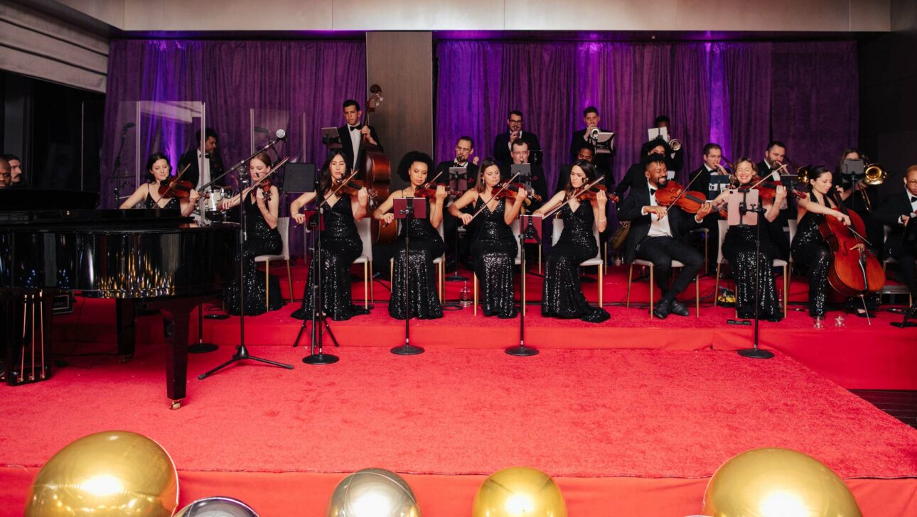 orchestral band playing on a red stage at an event.