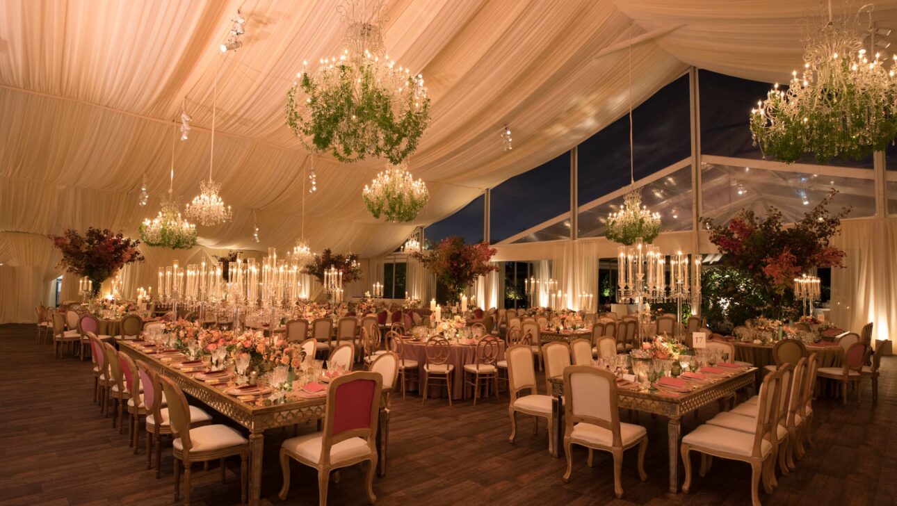 Elegant event venue space setup with chandeliers and floral arrangements.