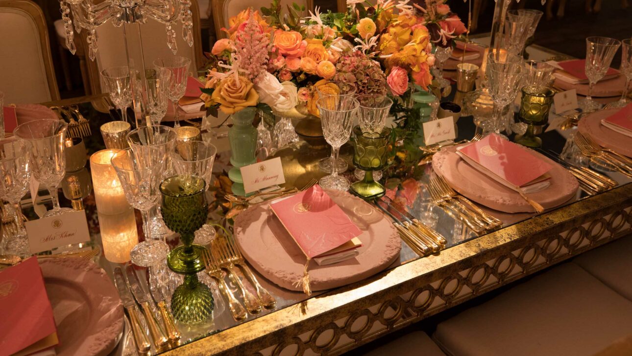 An elegant dining table set with floral centerpieces, crystal glassware, and pink place settings, curated by a leading event planning company.