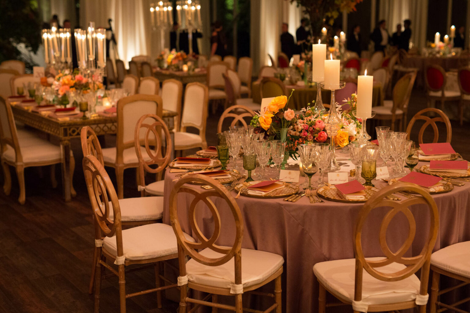 decorated dining tables with chairs and candle and floral centerpieces.