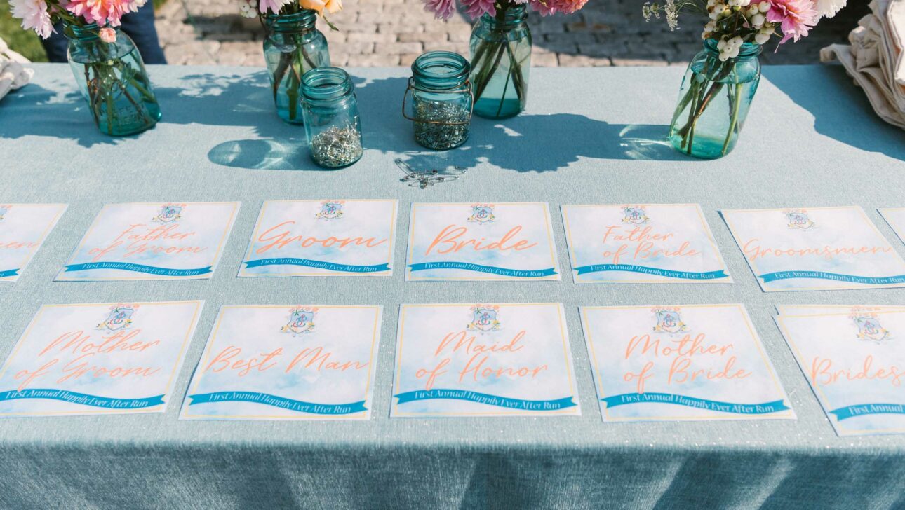 A table with neatly arranged wedding place cards alongside floral centerpieces, curated by an event planning company.