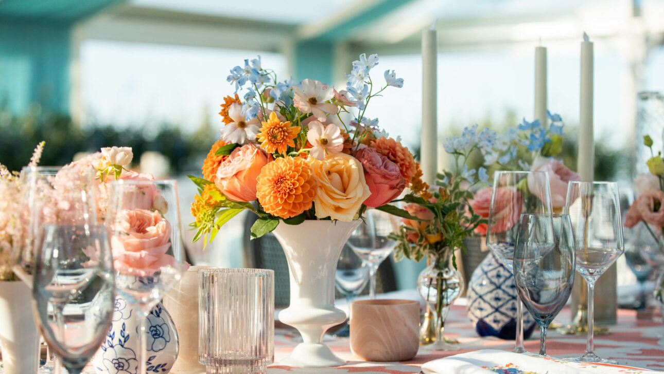 Elegant table setting with floral centerpiece in a well-lit event venue space.