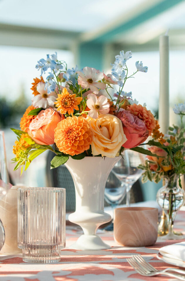 Elegant table setting with floral centerpiece in a well-lit event venue space.