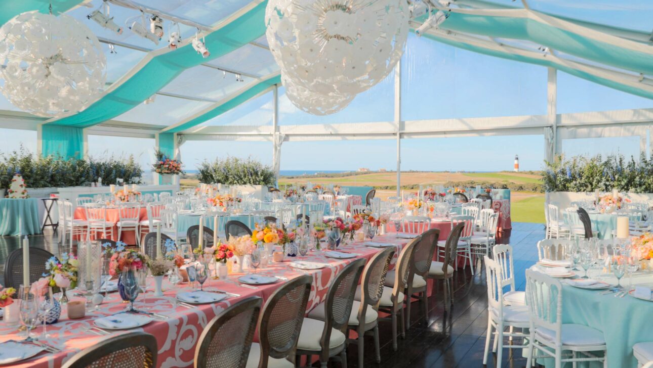 Elegant outdoor event venue space setup with tables, floral centerpieces, and a view of the countryside.