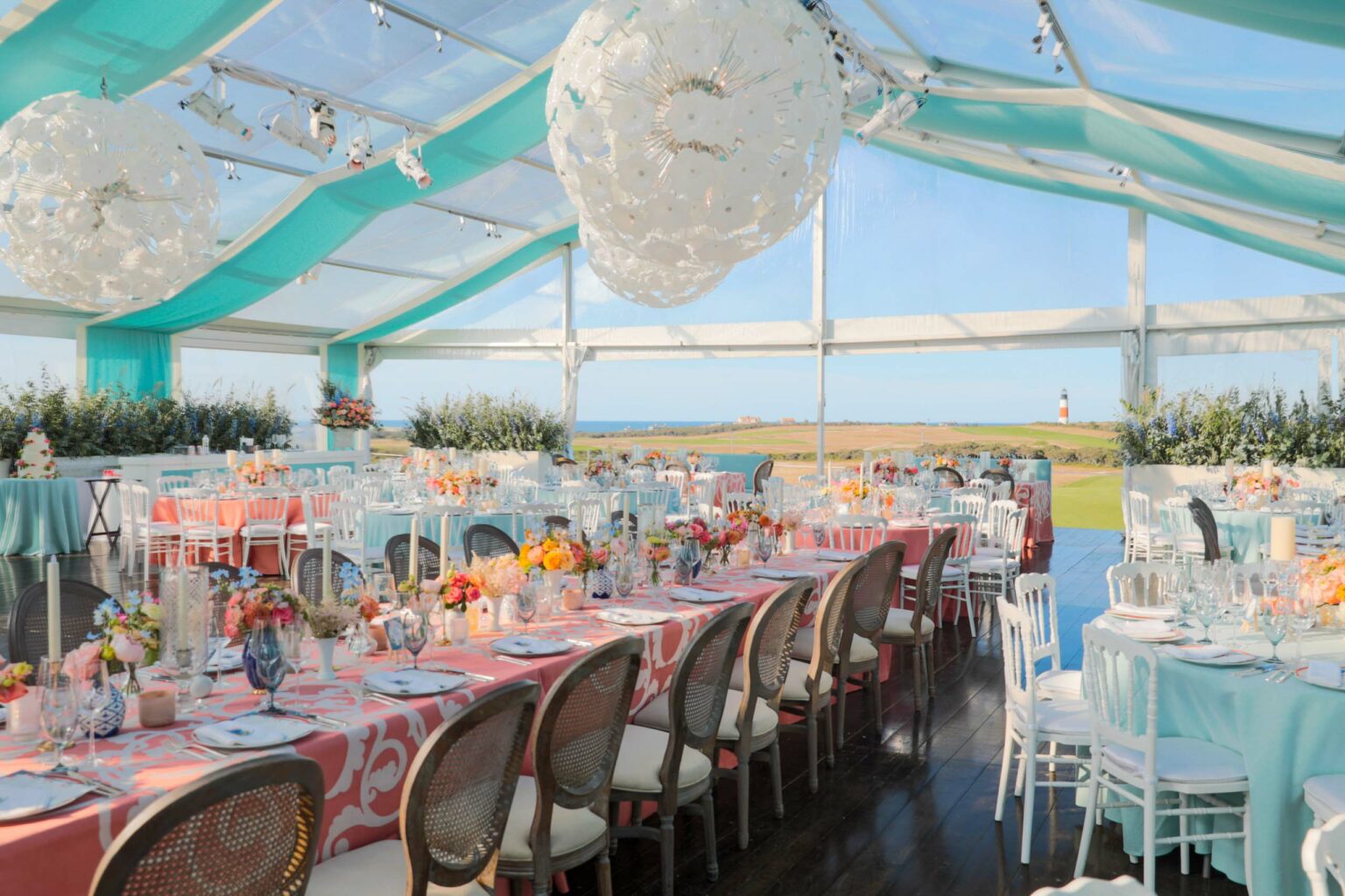 Elegant outdoor event venue space setup with tables, floral centerpieces, and a view of the countryside.