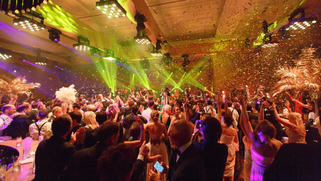 party in a ballroom with confetti in the air and green light beams.