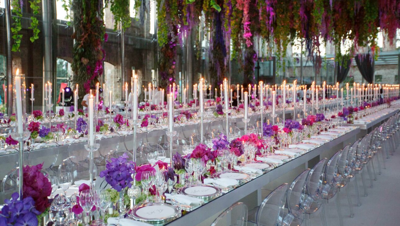 long decorated tables for wedding reception under floral arrangements.