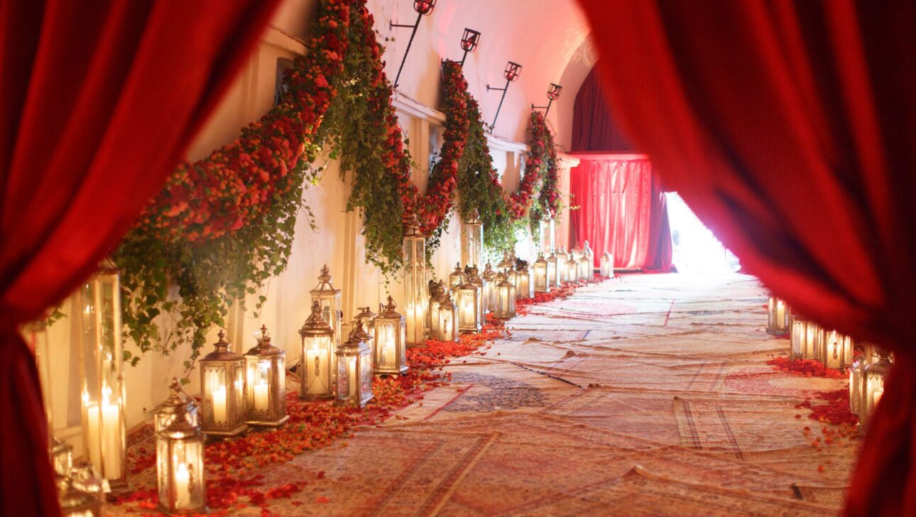 An ornate walkway adorned with lanterns, red drapery, and floral decorations, perfect for event venue spaces.