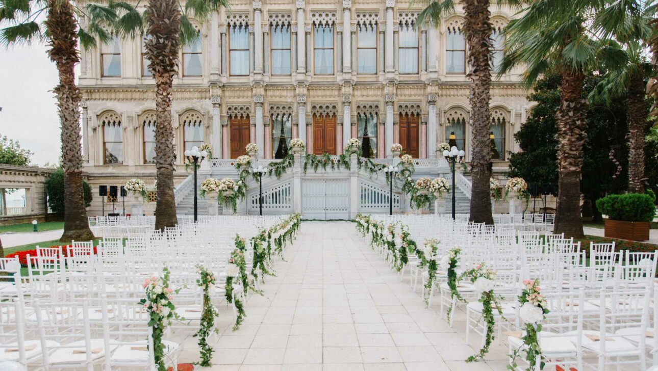 chairs set for a wedding ceremony in front of an elaborate building.