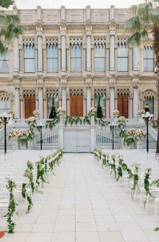 chairs set for a wedding ceremony in front of an elaborate building.