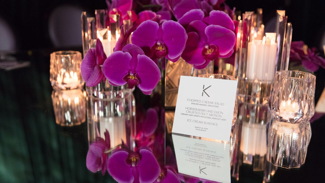 Elegant table setting with a menu, purple orchids, and candlelight organized by a top event planning company.