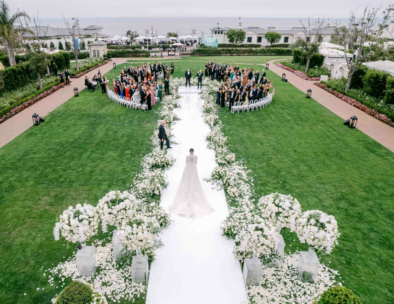 A bride walking down the aisle at an outdoor wedding ceremony, organized by a leading event planning company.