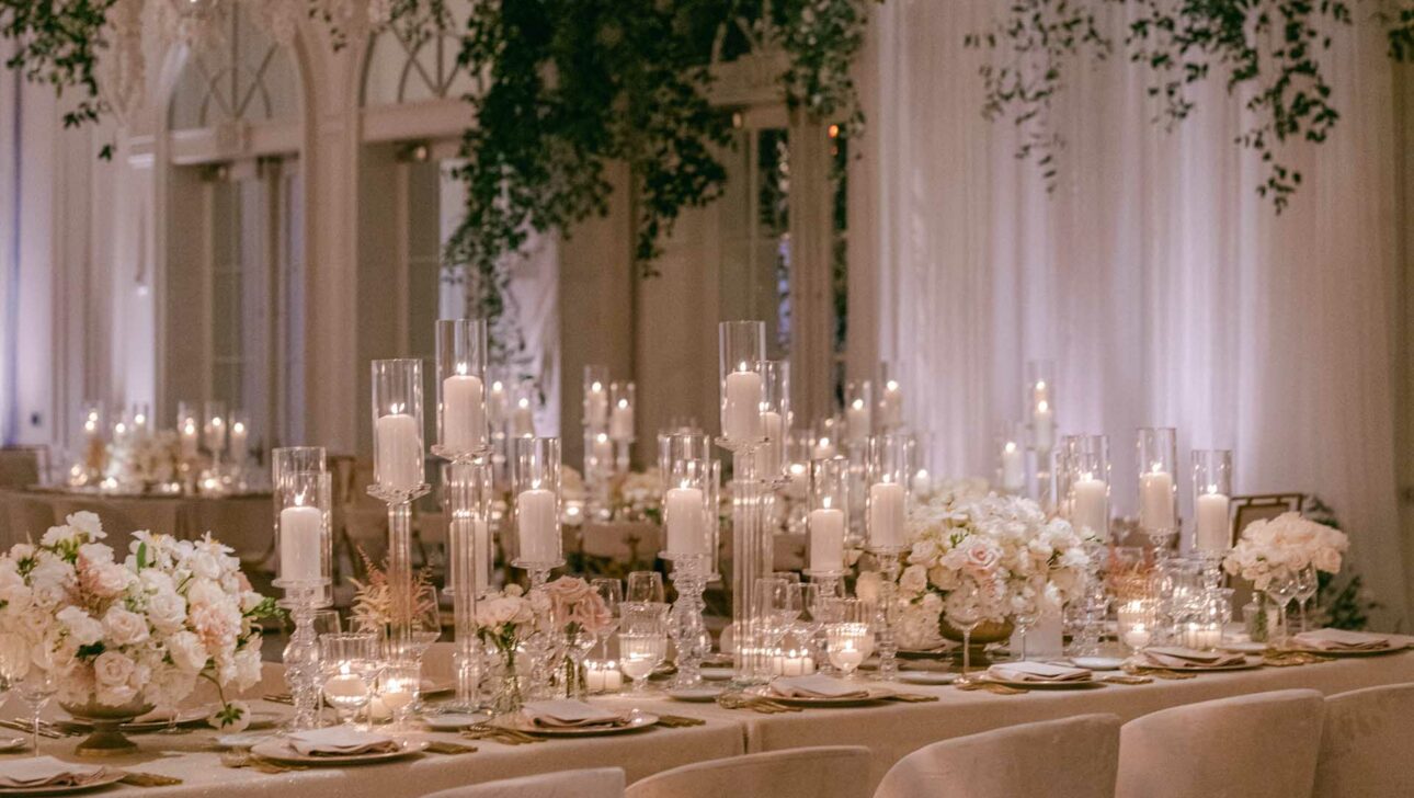 elegantly decorated dining tables with candles and floral centerpieces in a reception hall.