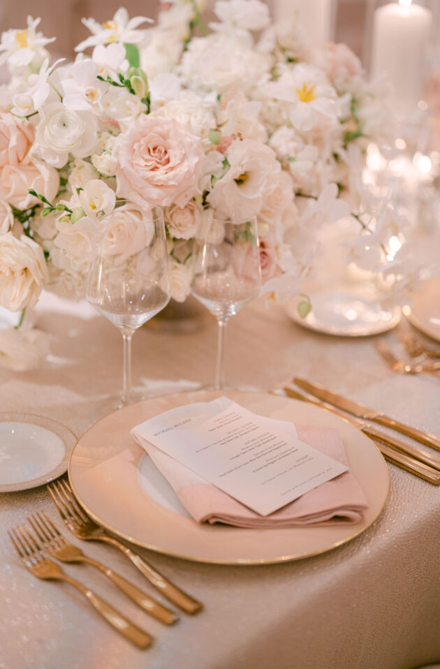 Elegant table setting with floral centerpiece and golden cutlery for a formal event, designed by an expert event planning company.