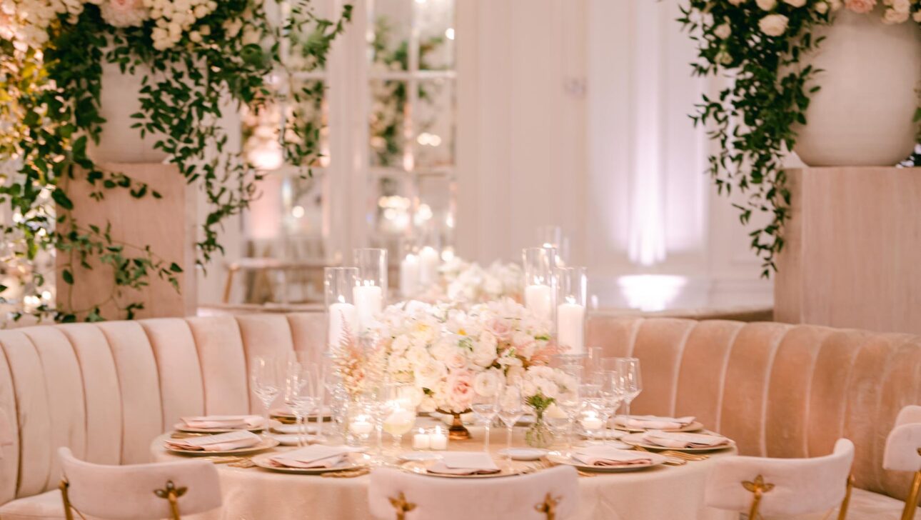 Elegant dining setup with floral arrangements and chandelier in a chic event venue space.