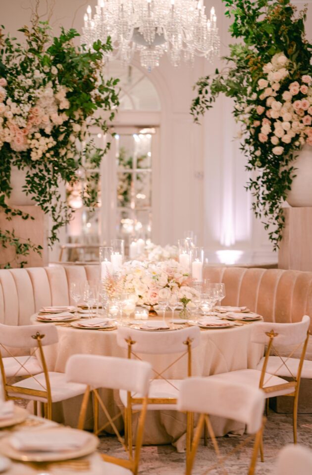 Elegant dining setup with floral arrangements and chandelier in a chic event venue space.