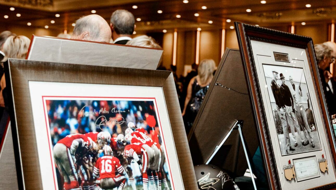 Memorabilia on display at a sports-themed event, organized by an event planning company, with attendees in the background.