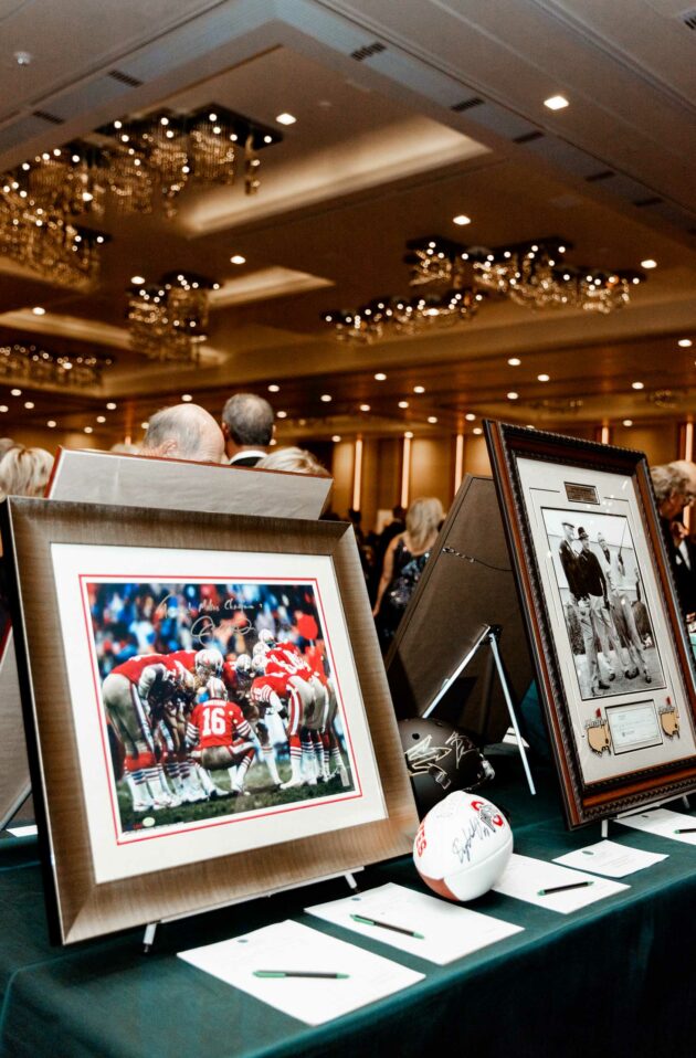 Memorabilia on display at a sports-themed event, organized by an event planning company, with attendees in the background.