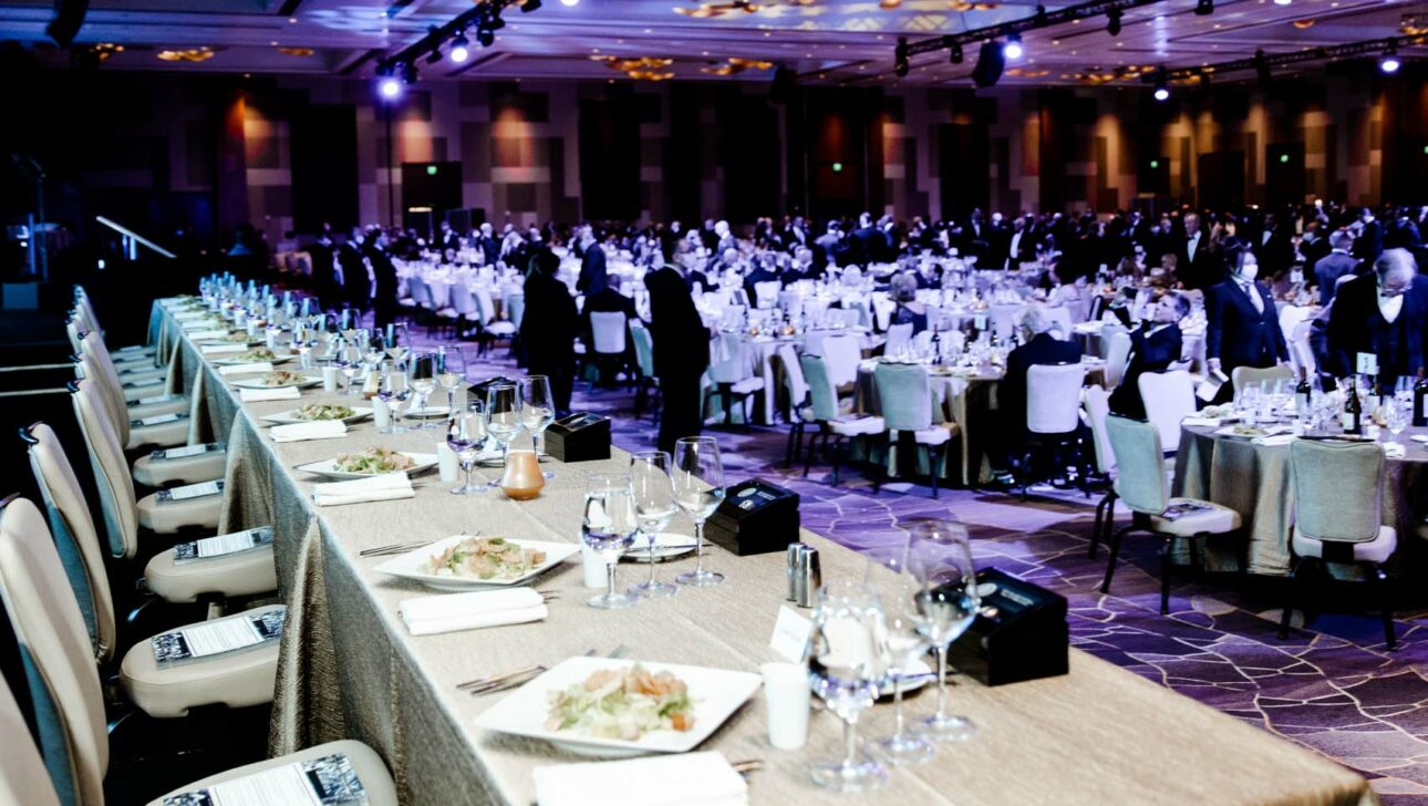 Elegant formal event planned by a professional event planning company in a large banquet hall with guests seated at round tables.
