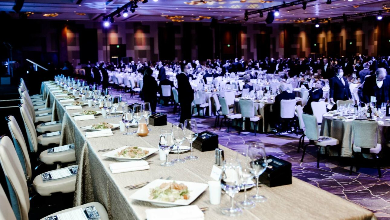 Elegant formal event planned by a professional event planning company in a large banquet hall with guests seated at round tables.