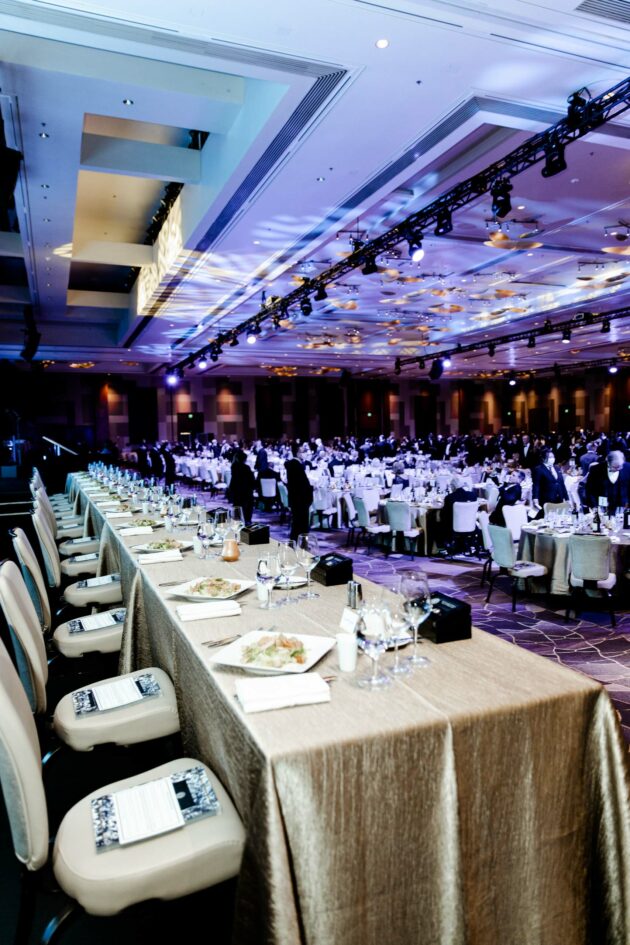 Elegant formal event planned by a professional event planning company in a large banquet hall with guests seated at round tables.