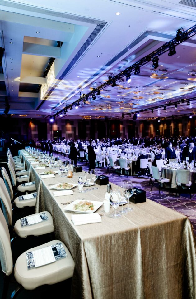 Elegant formal event planned by a professional event planning company in a large banquet hall with guests seated at round tables.