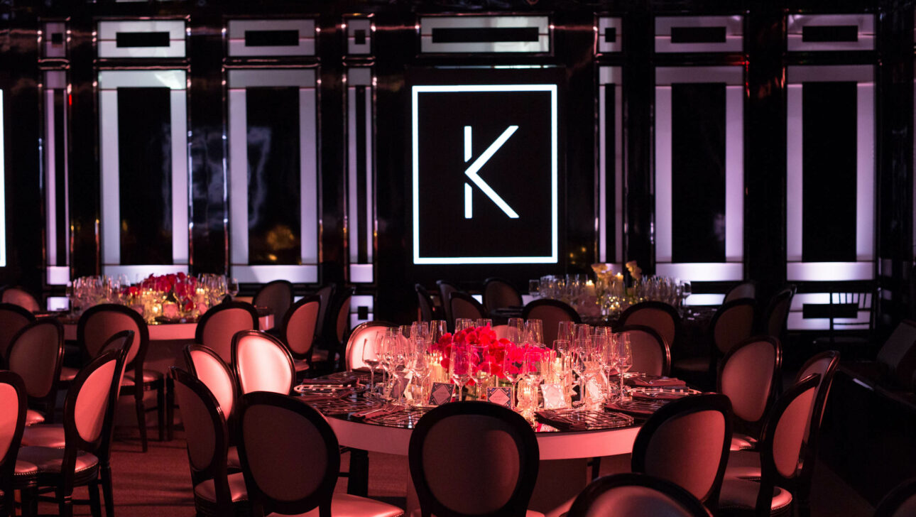 large k on the wall over a decorated dining table in a dark room.