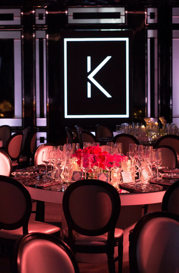 large k on the wall over a decorated dining table in a dark room.