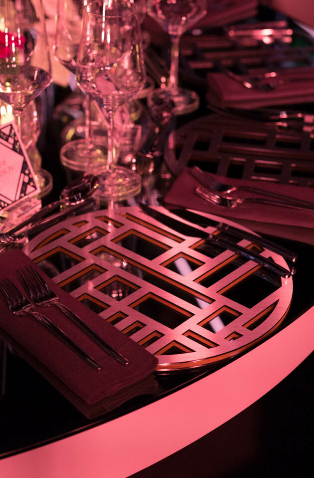 decorated place setting on a dark table in a neon pink lit room.