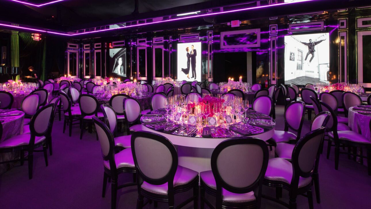 Elegant banquet setup with purple lighting in a modern event venue space.