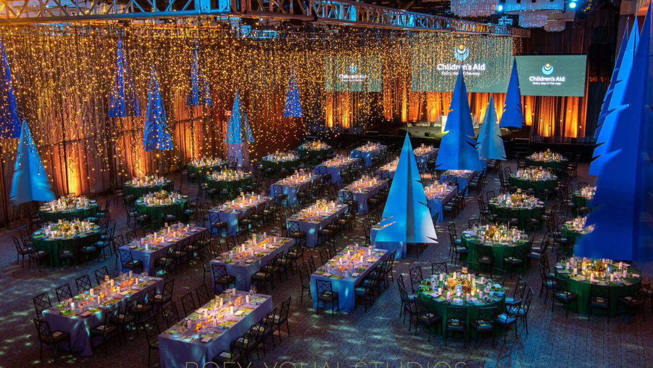An elegant gala event setup organized by an event planning company, with decorated tables, blue lighting, and a ceiling draped with sparkling lights.
