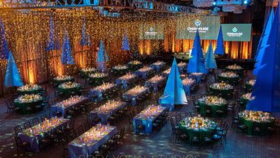 An elegant gala event setup organized by an event planning company, with decorated tables, blue lighting, and a ceiling draped with sparkling lights.