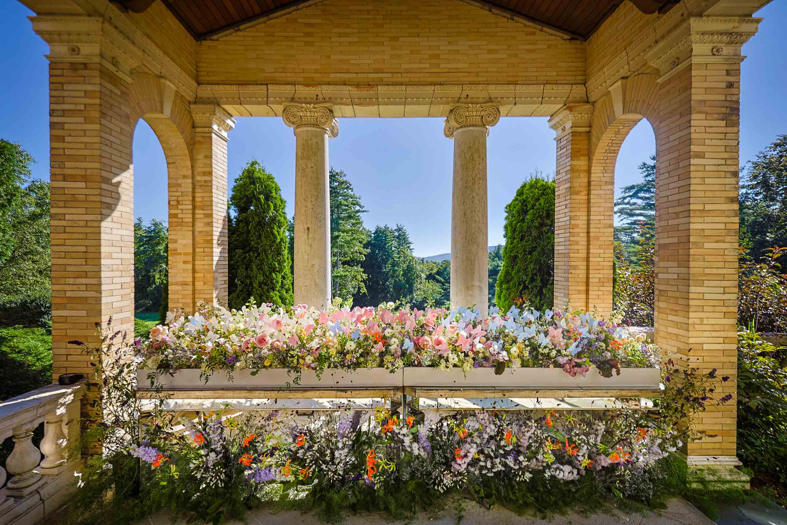 Classical pavilion adorned with vibrant floral arrangements on a sunny day, perfect for event venue spaces.