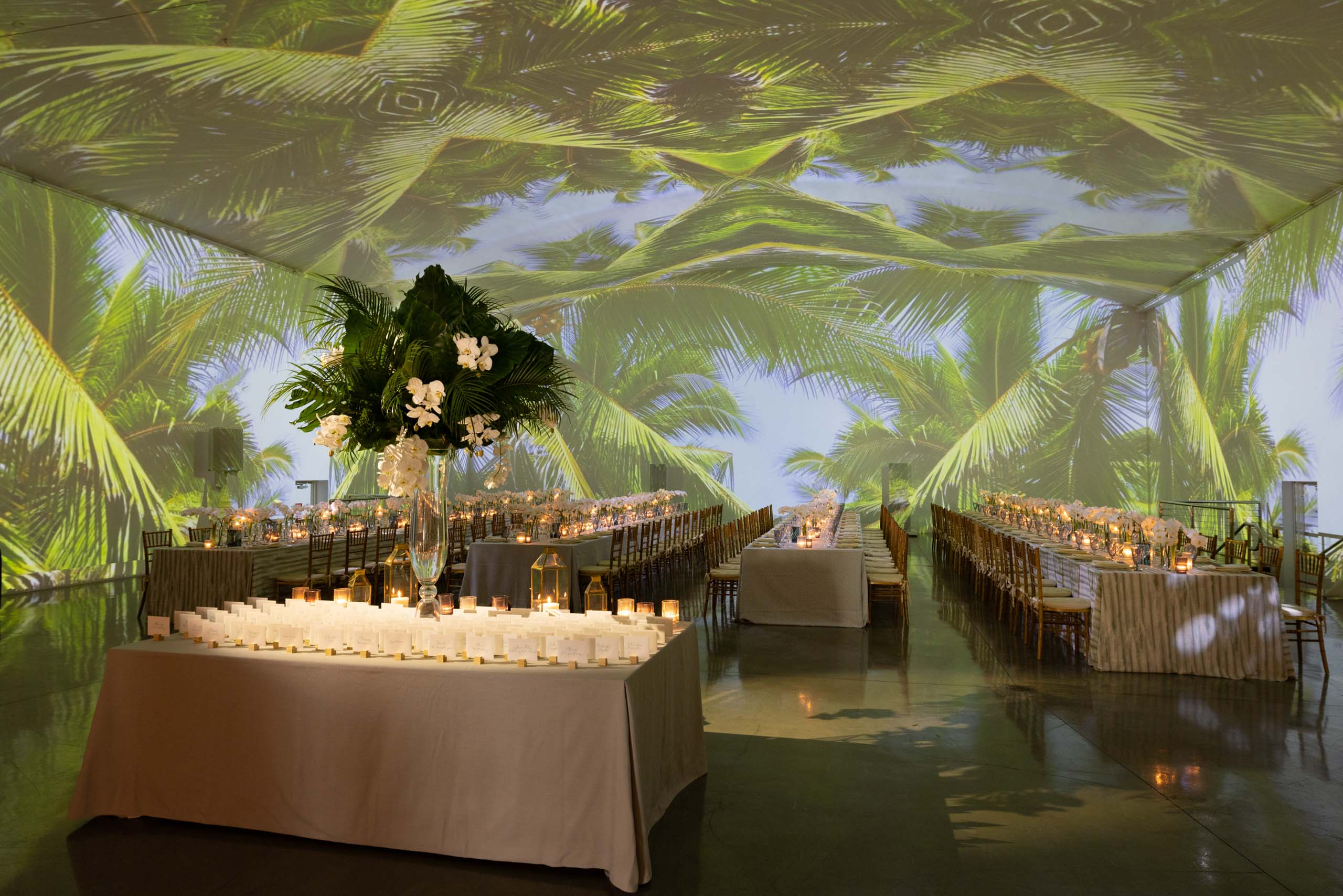 tables decorated for an event dinner in a tent with tropical decorations.